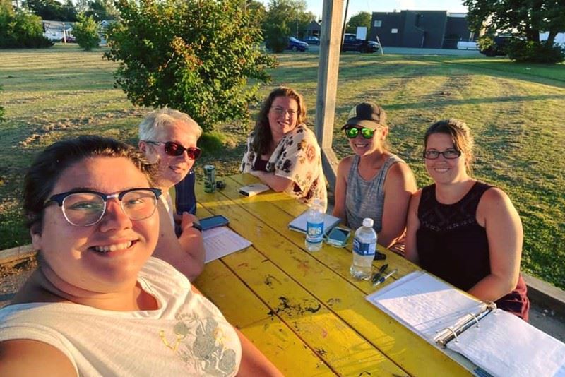 Five of the founding volunteers around a picnic table at Broidy Park