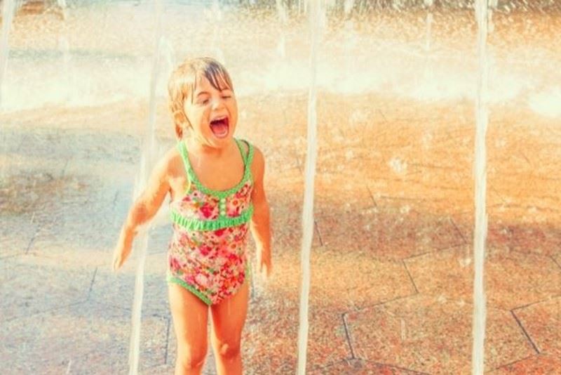 A small girl laughing under the water jets